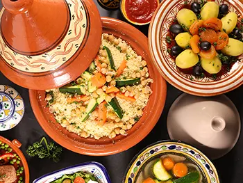 Couscous, tajines et bricks sont des plats emblématiques, souvent épicés avec du cumin, du ras el hanout et de la coriandre.